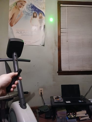 Customer holding the High Powered Laser, which is projecting a single bright green dot onto a wall.