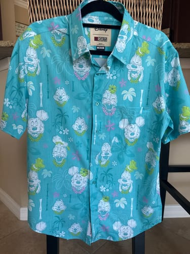 Customer's turquoise Disney "Island Smilin'" short sleeve shirt on a hanger, showing the all-over tiki-style character print.