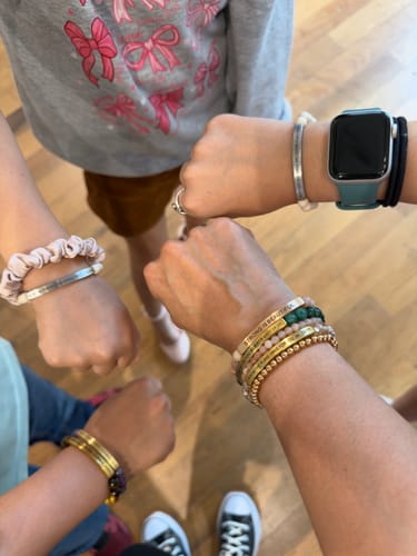 Customer and family join their wrists in a circle, showing off their beautiful bracelets.