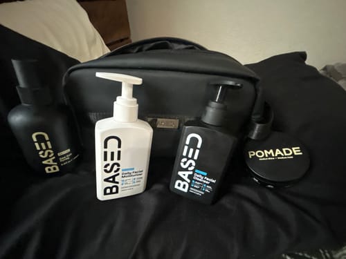 Customer's black Toiletry Bag displayed behind several grooming products on a dark surface.