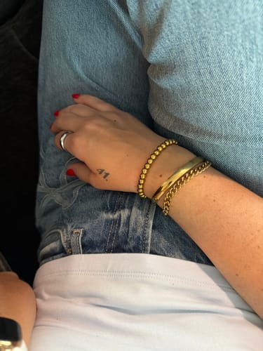 Reviewer showing their waterproof jewelry, mixing gold bracelets and a silver ring for a stylish two-toned look.
