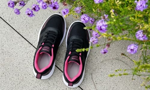 Reviewer's black Ortho Air shoes with pink lining, shown outdoors on a stone patio next to flowers.