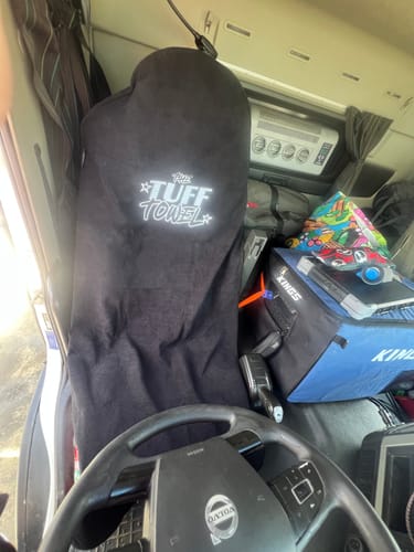 Customer's black Tuff Towel seat cover fitted over the driver's seat inside a truck cabin.