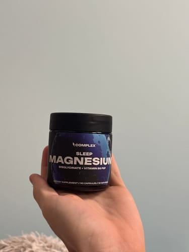 A reviewer holds a black jar of Complex Sleep Magnesium in their hand.