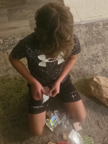 Reviewer's child kneeling on the floor wearing the black Joshua 1:9 Youth Performance Shorts.