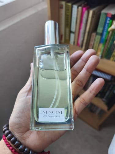 Un cliente sostiene en la mano la botella de cristal rectangular del perfume M032, que está casi llena.