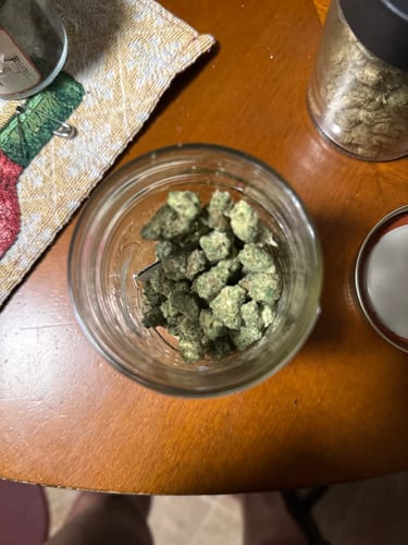 Reviewer's small, green Lemon Gas Mask - Exotic Smalls buds inside an open glass jar on a table.