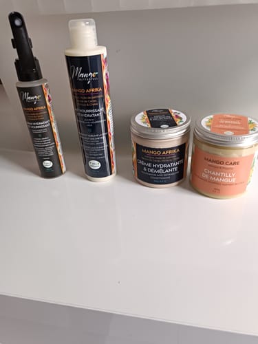 Un client montre le Spray Hydratant Mango Afrika à côté de la crème hydratante et de la chantilly de la même gamme.