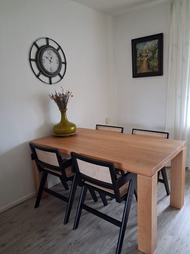 Klantfoto van de zwarte rotan Gunn eetkamerstoelen aan een houten eettafel.