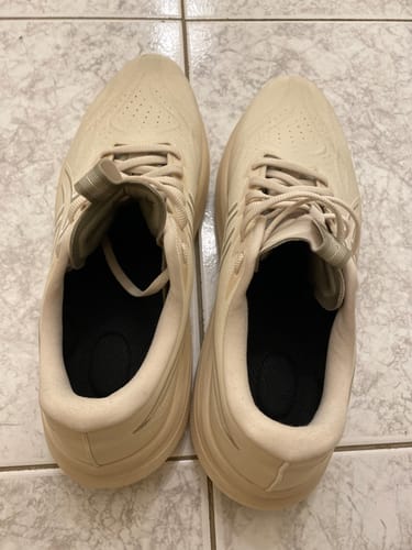 Reviewer's view of the black Comfort 4D Insoles placed inside a pair of light beige sneakers.