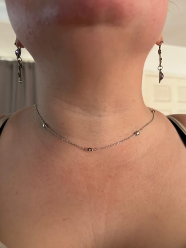 Close-up of a reviewer wearing the delicate Jane Heart Station Necklace, highlighting the small heart accents on the chain.