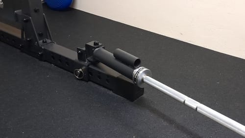 Ein Rezensent zeigt die R7 Landmine, wie sie mit einer Hantelstange am unteren Teil eines Racks befestigt ist.