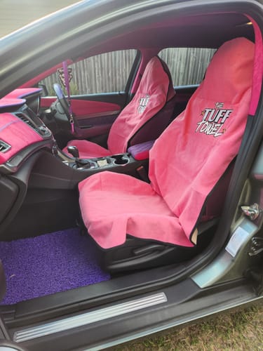 Customer's two pink Waterproof Car Towel Seat Covers installed on the front seats inside a brightly colored car.