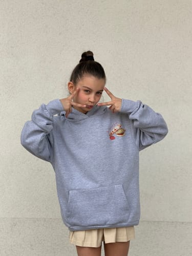 Customer wearing the oversized strawberry grey hoodie, showing the small front graphic and kangaroo pocket.