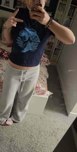 Customer wearing the dark sandy baby tee with a blue graphic in a mirror selfie.