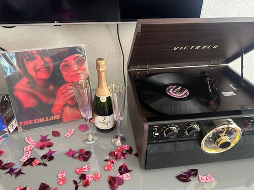 Customer's custom vinyl record playing on a turntable, with the personalized photo album cover displayed alongside.