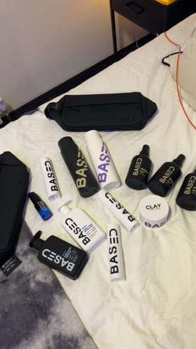 Customer's collection of various BASED brand products, including the Revitalizing Trio, displayed on a white bed.