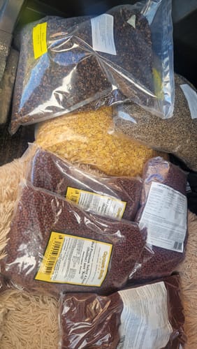 Recensent toont de ontvangen zakken Red Premium Select Pellets samen met andere soorten voerpellets.