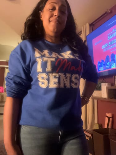 Reviewer showing the roomy fit of the blue Make It Make Sense Sweatshirt while wearing it with jeans.