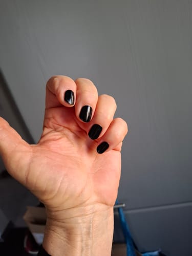 Hand einer Kundin mit kurzen, glänzend schwarz lackierten Nägeln mit den UV Gel Wraps.