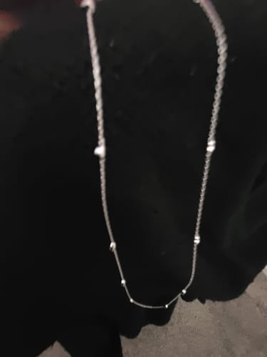 Customer's delicate Jane Heart Station Necklace with small heart accents displayed against a dark surface.