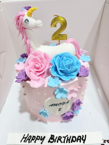 Customer's pink Unicorn Lush Hair Cake with a unicorn topper, colorful flowers, and a gold '2' candle for a birthday.