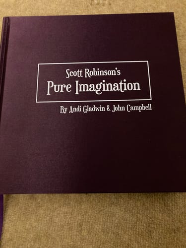 Reviewer's 'Pure Imagination by Scott Robinson' book, showing its simple dark purple cover on a table.