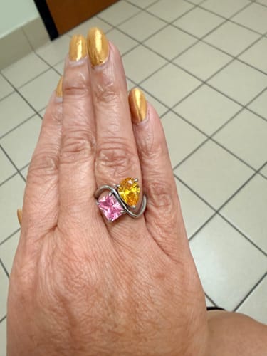 Reviewer's hand wearing the Navae Birthstone Ring with a pink radiant-cut and a yellow pear-cut stone.