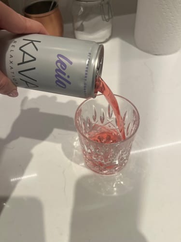 Customer pouring a pink Leilo Kava Tonic from the can into a decorative glass.