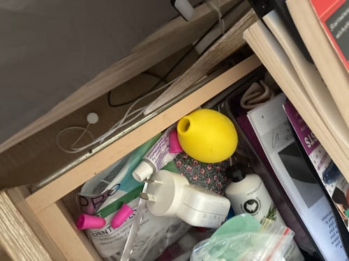 Customer's yellow Lem Clitoral Massager stored inside a cluttered wooden drawer with other items.