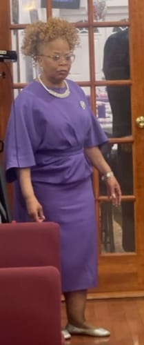 Reviewer standing indoors wearing the purple pleated midi dress with puff sleeves.