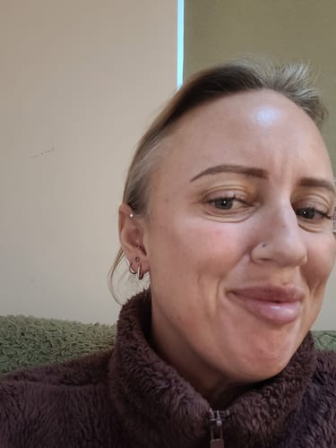 Reviewer smiling, showing the Small Solitaire flatback Silver stud worn in her upper cartilage piercing.