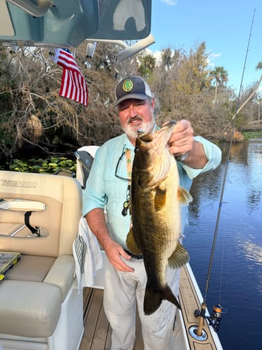 Reviewer on a fishing boat holding a large fish, with the American Flag mounted in the background.