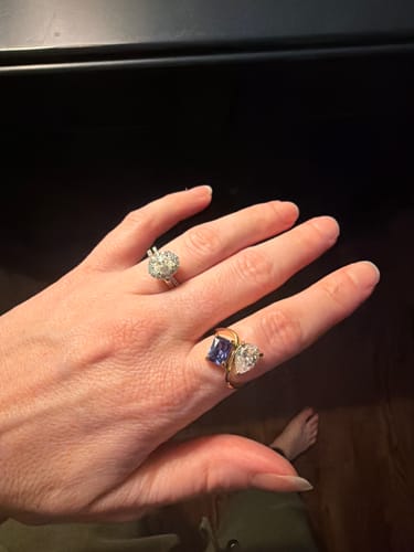 Reviewer's hand wearing the gold Navae Birthstone Ring with a blue and clear stone.