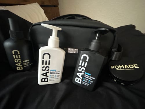 Reviewer's Daily Skincare Duo displayed on a black surface with a pomade, sea salt spray, and a black toiletry bag.