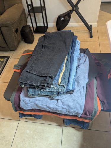 Customer's pile of folded wholesale denim jackets in assorted blue and black washes.