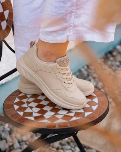 Reviewer wearing the beige Soft Step shoes, with one foot placed on a small mosaic table outdoors.