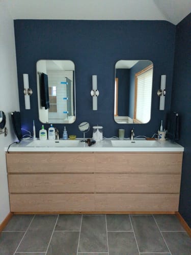 Customer's large, light wood Monterey Modern Vanity with double sinks, installed in a bathroom with dark blue walls.