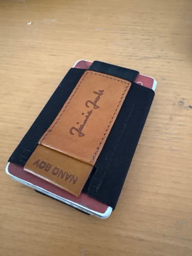 Customer's black Nano Boy card holder wallet with a tan leather pull-tab, shown full of cards on a table.