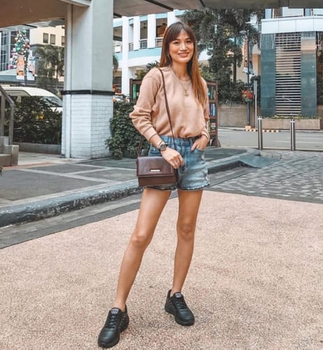 Reviewer standing outdoors wearing black Soft Stride shoes with denim shorts and a sweater.