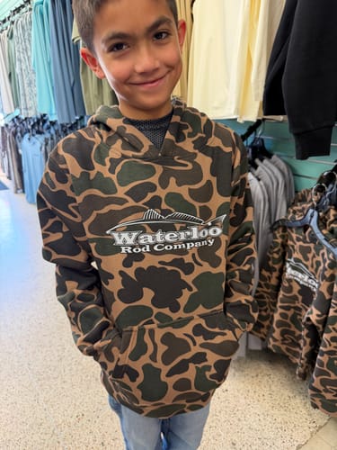 Reviewer's child wearing the Waterloo Youth Duck Camo Pullover Hoodie with hands in the front pouch pocket.