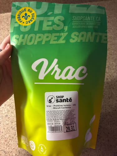 Un client tient le sac vert de Protéine Isolate en vrac de Shop Santé, saveur Biscuit Confettis.