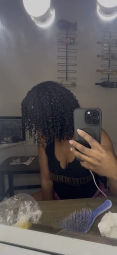 Reviewer's mirror selfie showing defined, curly hair after using the Tropical Oasis Hair Gel.
