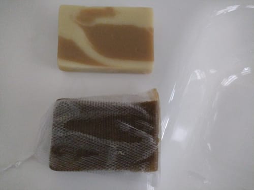 Ein Kunde zeigt zwei Herbal-Love Haarseifen: eine marmorierte und eine zweite in einem Netzbeutel.