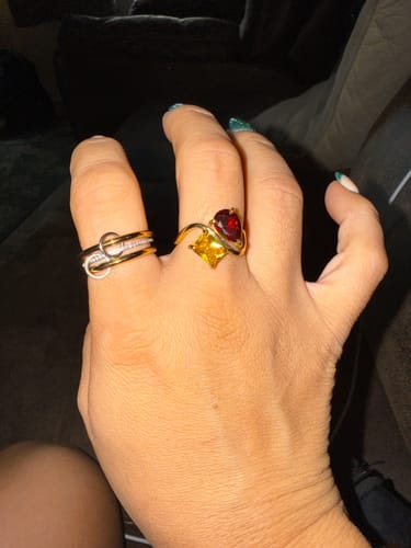 Customer's hand wearing the Navae Birthstone Ring with its vibrant red and yellow stones on a gold band.