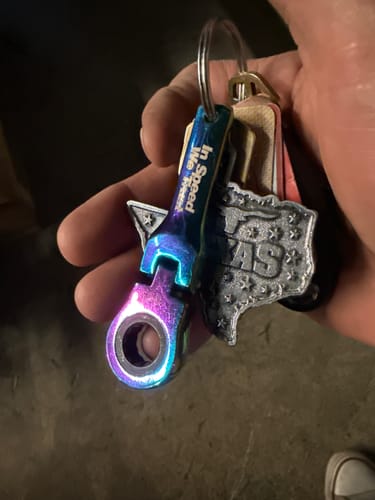 Customer holding a key ring with the rainbow-colored 10mm Wrench Keychain attached.