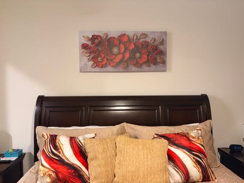 Customer's red Modern Blossom Wall Art hanging on a wall centered above a dark wood headboard.