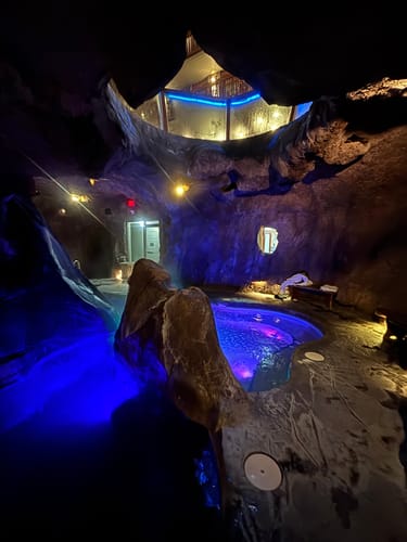 Reviewer's photo of an indoor grotto with a hot tub and blue lighting.