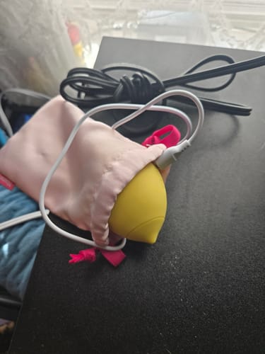 Customer's yellow Lem massager in a pink pouch with the charging cable plugged in.