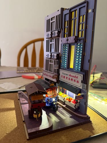 Customer's assembled Bangkok Yaowarat Book Nook Kit from the side, showing a lit purple building and tuk-tuk.